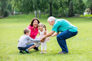 Image of a grandmother and grandfather playing with their grandchildren to illustrate the long term care and later life advice offered by Cathedral Independent Financial Planning Ltd